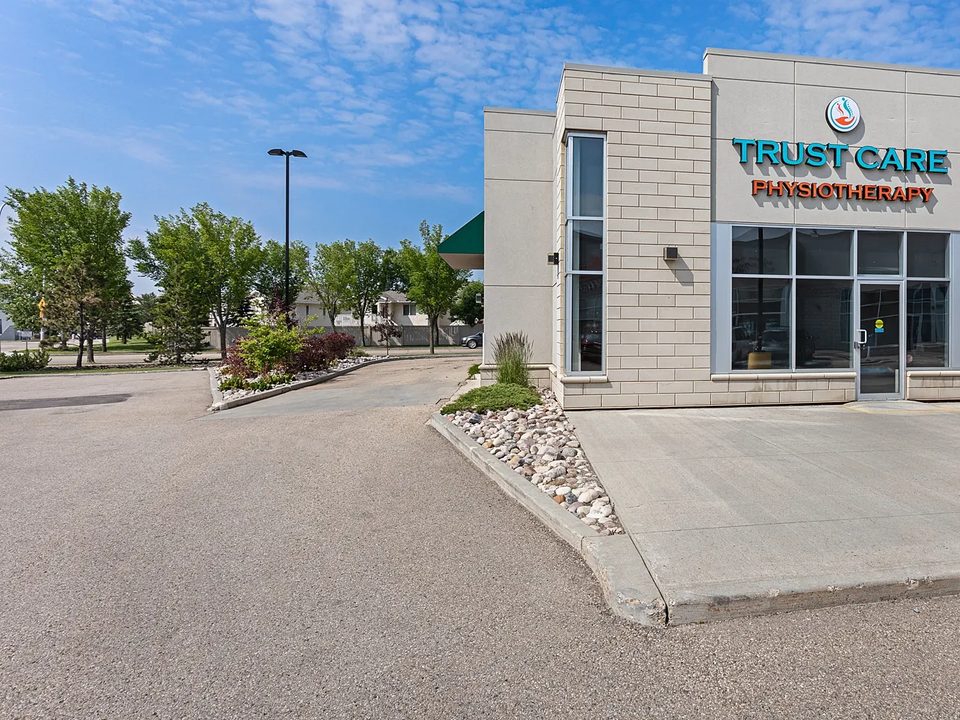 The Trust Care Physiotherapy building on Miller Boulevard NW, with its sign and parking in front